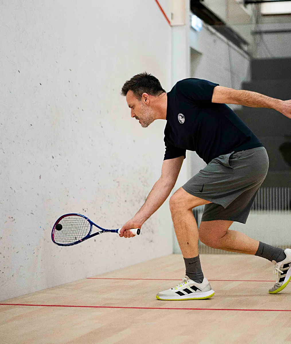 Man playing a low squash shot with Vadetep squash racket