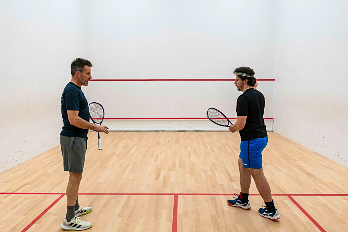 Two men facing each other with Vadetep squash rackets on squash court